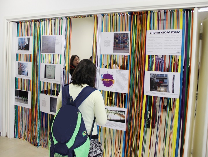 Jovem observa instalação colorida com exposição de fotos