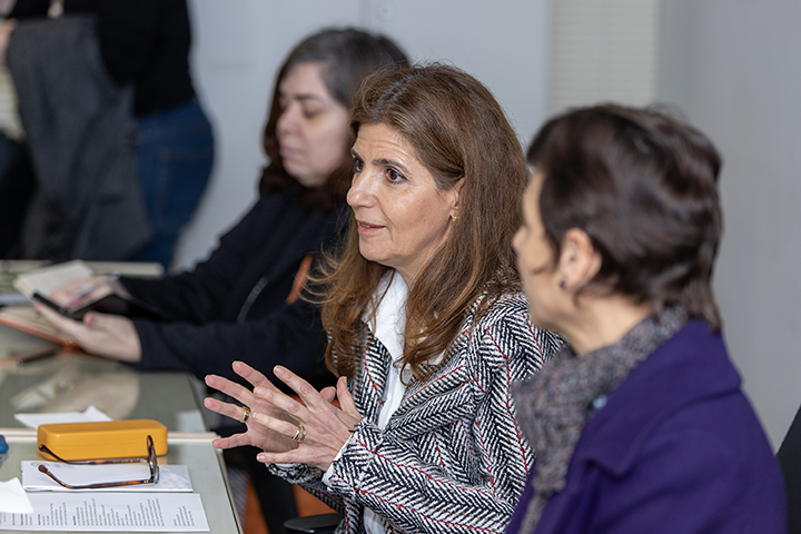 imagem também mostra pessoas envolvidas em uma reunião ou discussão. Uma mulher em primeiro plano, a secretária Ana Estela Haddad, parece estar falando, com outras pessoas ouvindo atentamente.