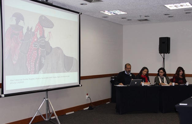 Apresentação do professor André Tavares, sentado à mesa, realizada durante o evento